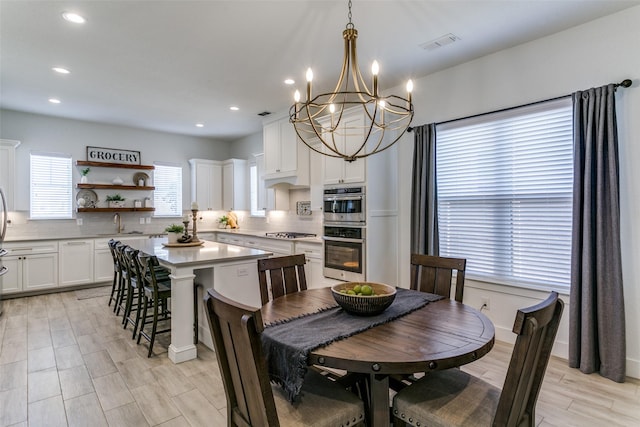 dining room with sink, light hardwood / wood-style flooring, and a notable chandelier