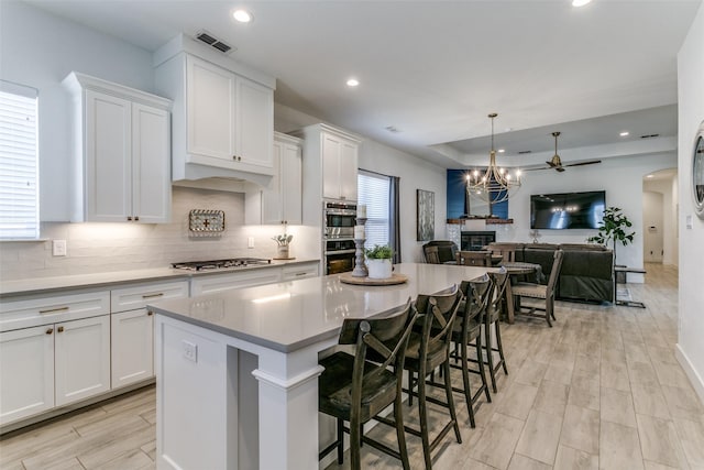 kitchen with white cabinetry, a center island, a breakfast bar area, and decorative backsplash