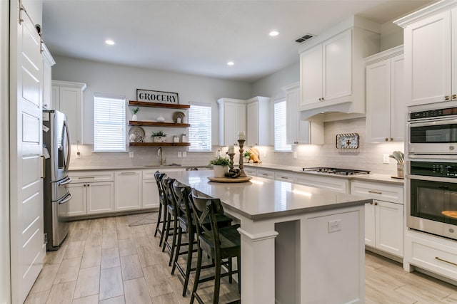 kitchen with white cabinetry, sink, stainless steel appliances, and a kitchen island