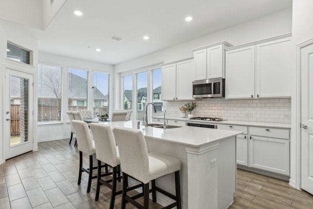 kitchen featuring sink, stainless steel appliances, an island with sink, and white cabinets