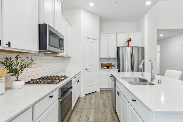 kitchen with light stone countertops, white cabinetry, appliances with stainless steel finishes, and sink