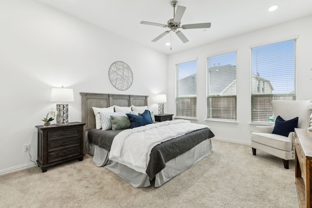 bedroom with ceiling fan, light colored carpet, and multiple windows