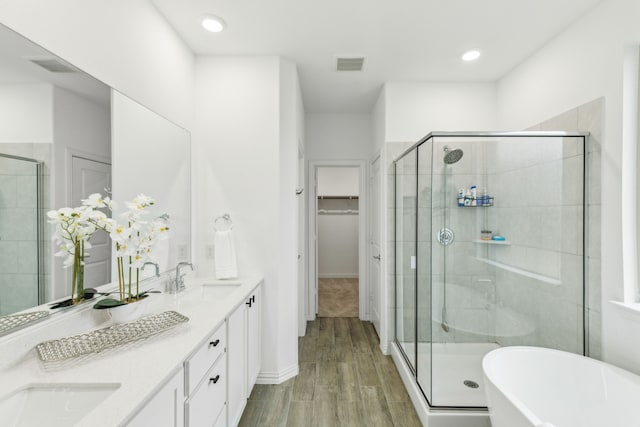 bathroom featuring wood-type flooring, plus walk in shower, and vanity