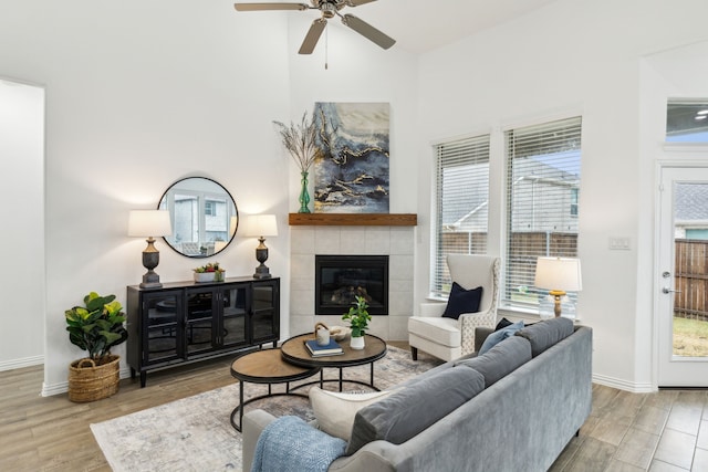 living room featuring hardwood / wood-style flooring, a fireplace, ceiling fan, and a high ceiling