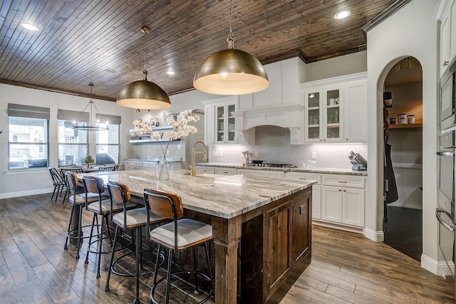 kitchen with a spacious island, stainless steel gas cooktop, hanging light fixtures, and white cabinets