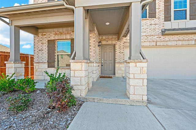 view of exterior entry with a garage and a porch