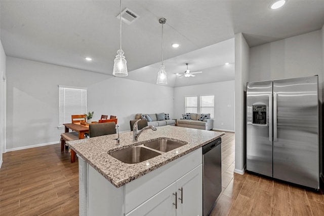 kitchen with sink, white cabinetry, decorative light fixtures, a center island with sink, and stainless steel appliances