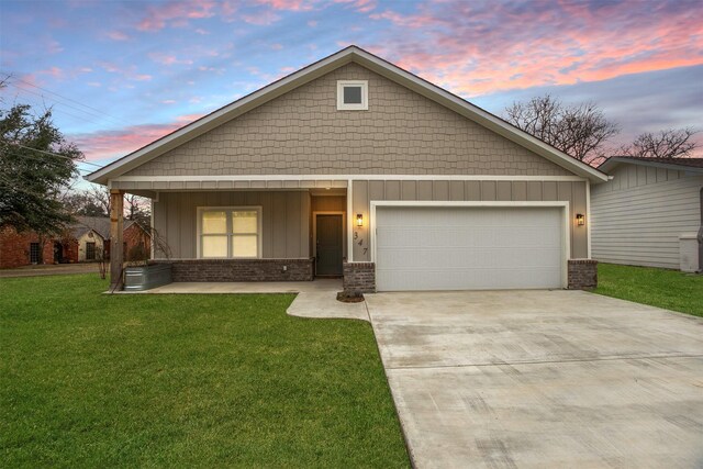 view of front of house featuring a yard, covered porch, and a garage