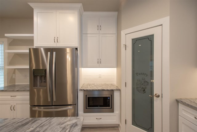 kitchen featuring white cabinetry, appliances with stainless steel finishes, and light stone counters