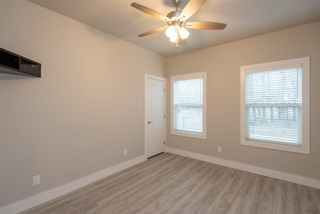 unfurnished room featuring a healthy amount of sunlight, ceiling fan, and light hardwood / wood-style flooring