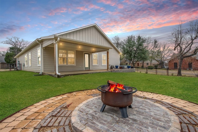 back house at dusk featuring a fire pit and a lawn