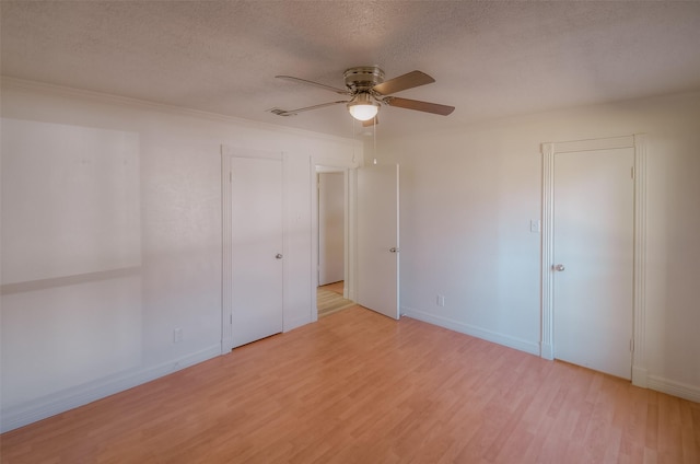 empty room with ceiling fan, crown molding, a textured ceiling, and light wood-type flooring