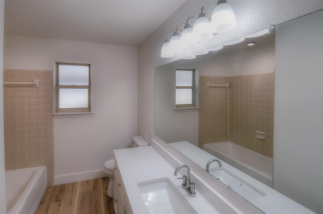 full bathroom with vanity, tiled shower / bath, hardwood / wood-style flooring, and a healthy amount of sunlight