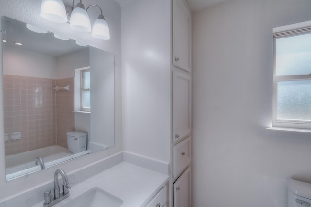 full bathroom featuring vanity, tiled shower / bath, an inviting chandelier, and toilet