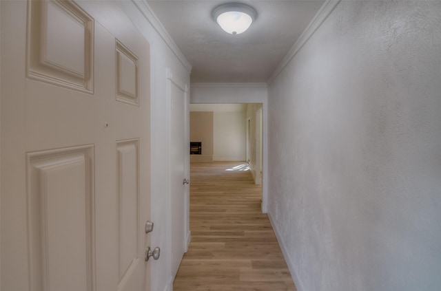 hall with ornamental molding and light hardwood / wood-style floors