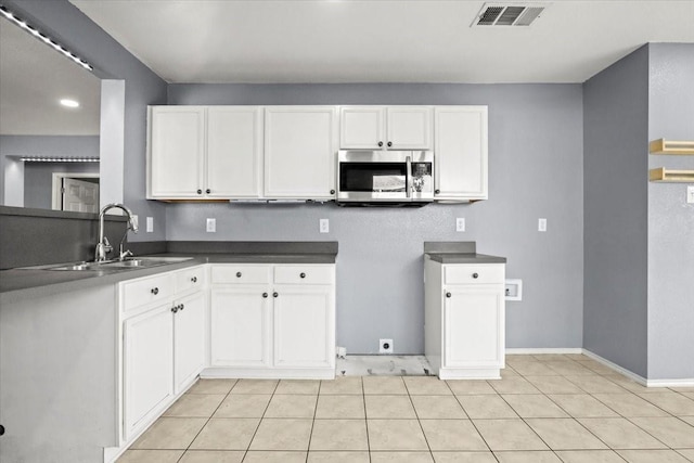 kitchen featuring sink, light tile patterned floors, and white cabinets