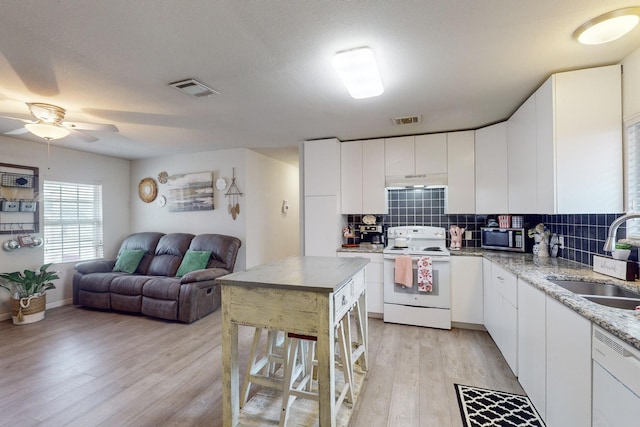 kitchen with white cabinetry, sink, light wood-type flooring, backsplash, and white appliances