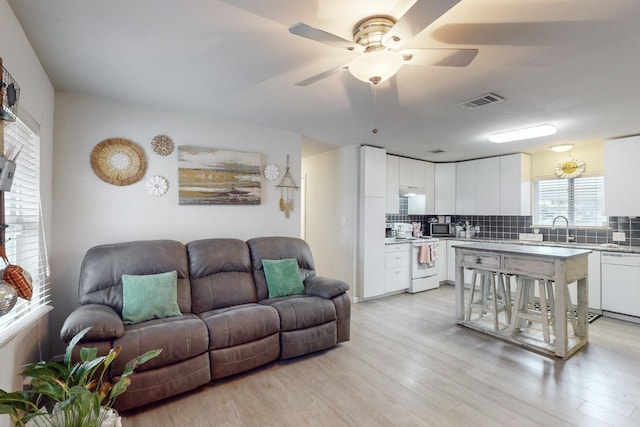 living room with ceiling fan, light hardwood / wood-style floors, and sink