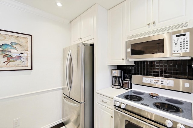 kitchen featuring stainless steel appliances, ornamental molding, white cabinets, and decorative backsplash