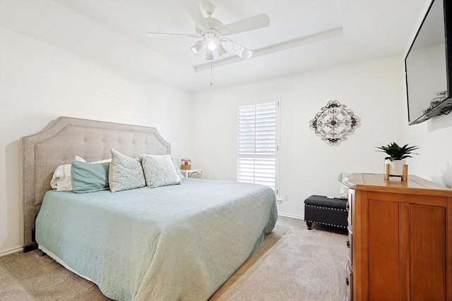 bedroom with light carpet, ceiling fan, and a tray ceiling