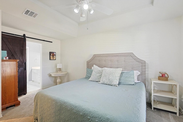 carpeted bedroom with ensuite bathroom, a barn door, and ceiling fan