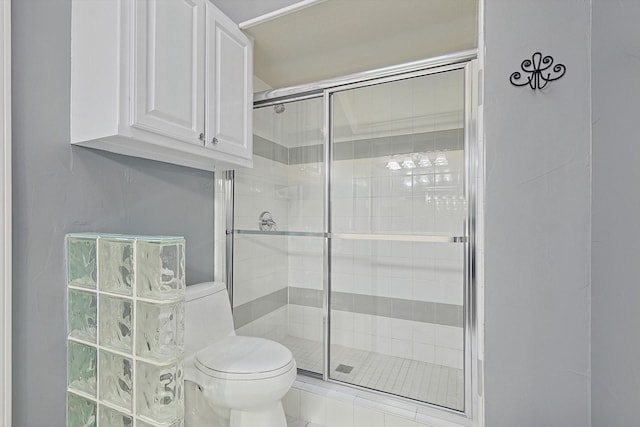 bathroom featuring a shower with shower door and toilet