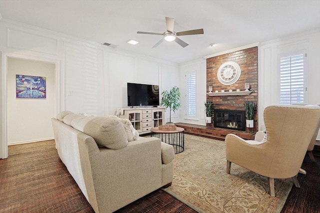 living room with a brick fireplace, ornamental molding, hardwood / wood-style floors, and ceiling fan