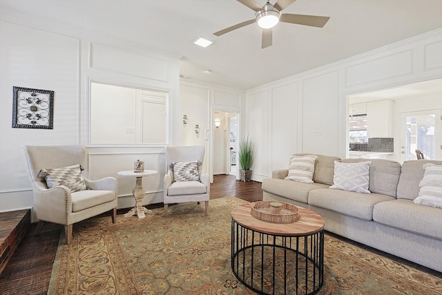 living room with ornamental molding, dark wood-type flooring, and ceiling fan