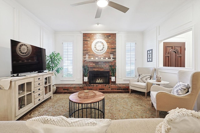 living room with a fireplace, ornamental molding, and ceiling fan