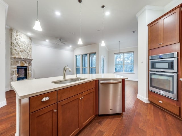 kitchen featuring an island with sink, stainless steel appliances, sink, and hanging light fixtures