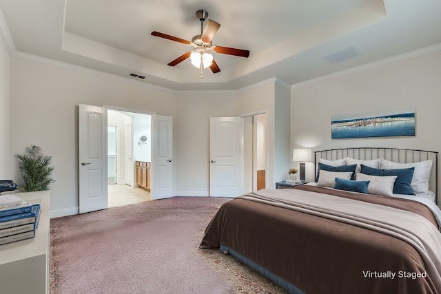 bedroom with crown molding, connected bathroom, a tray ceiling, and light carpet