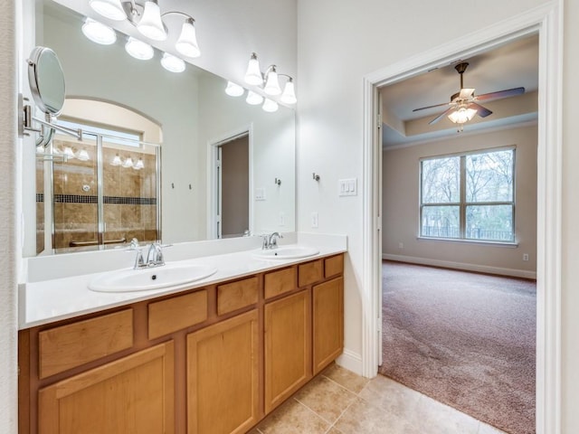 bathroom featuring tile patterned flooring, vanity, ceiling fan, a tray ceiling, and a shower with door