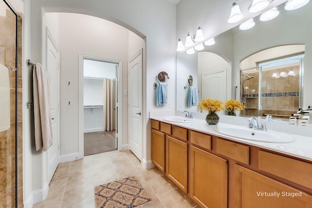 bathroom with a shower with door, vanity, and tile patterned flooring