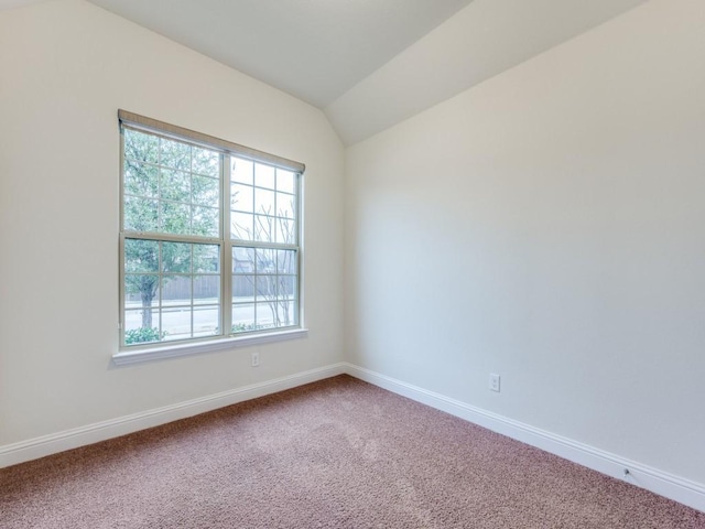 carpeted spare room featuring vaulted ceiling