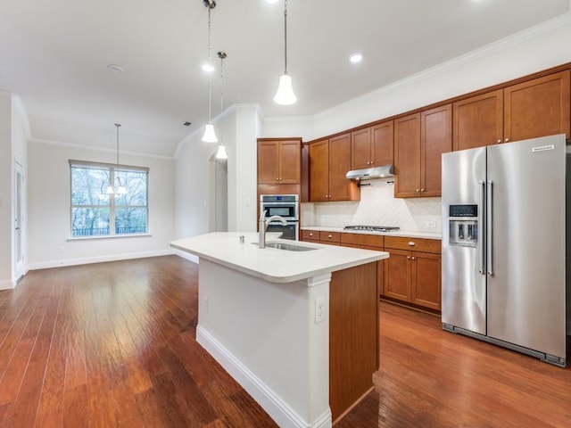 kitchen with pendant lighting, sink, ornamental molding, a kitchen island with sink, and stainless steel appliances