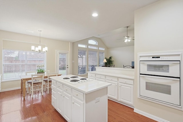 kitchen featuring white cabinetry, white appliances, plenty of natural light, and a center island