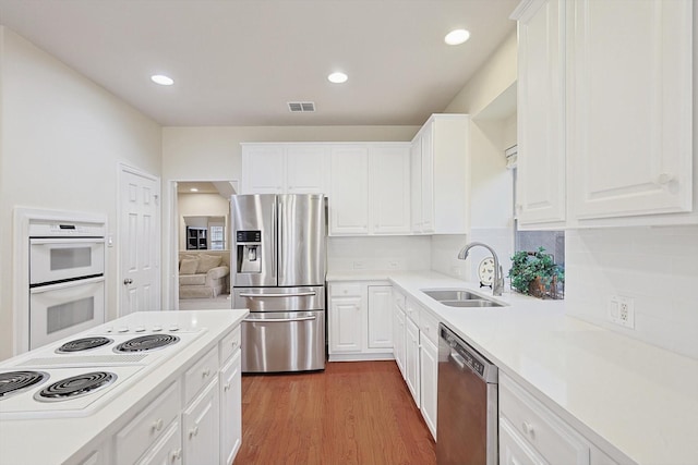 kitchen featuring sink, tasteful backsplash, appliances with stainless steel finishes, hardwood / wood-style floors, and white cabinets