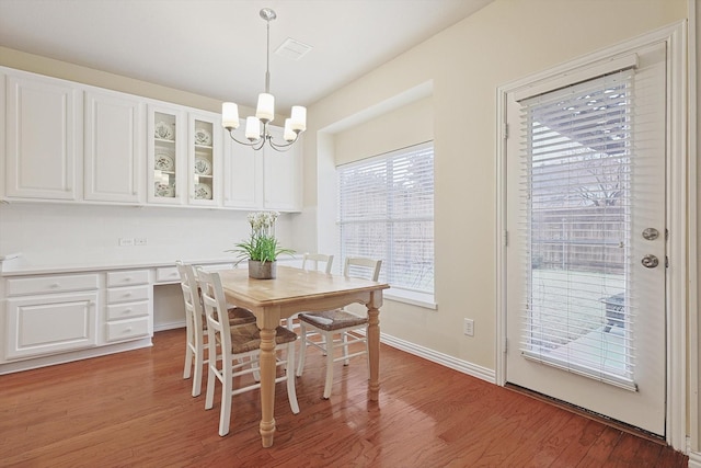 dining room featuring wood-type flooring, built in desk, and a notable chandelier