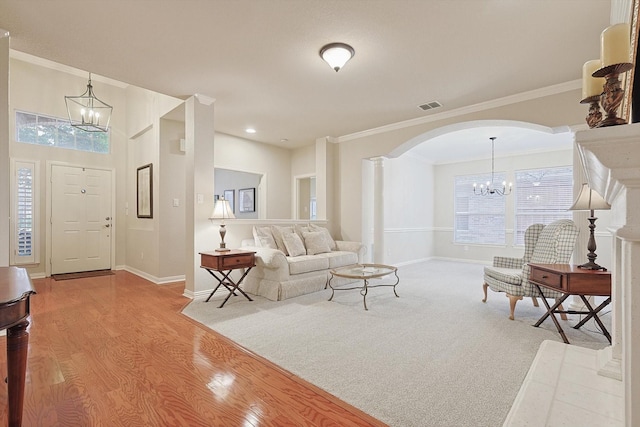 living room featuring crown molding, light hardwood / wood-style floors, and a chandelier