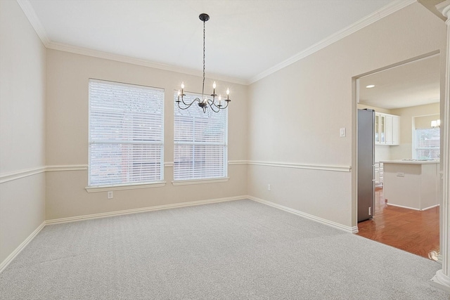 spare room with crown molding, a chandelier, and carpet