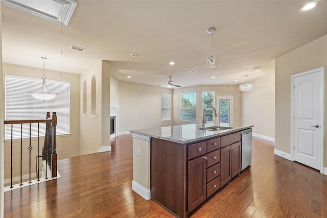 kitchen featuring pendant lighting, stainless steel dishwasher, sink, and a center island with sink