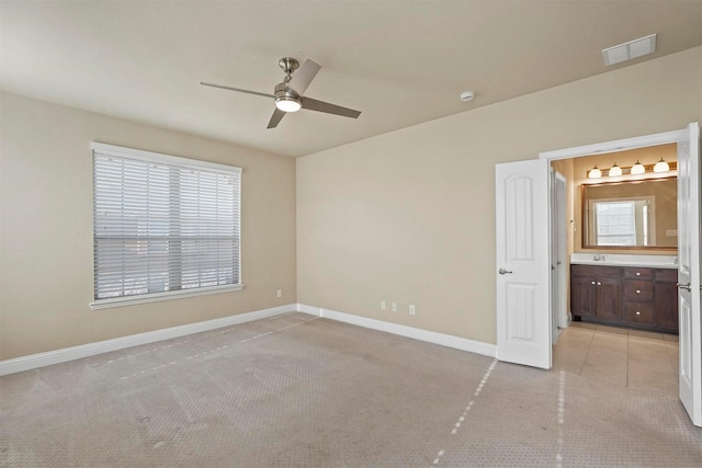 unfurnished bedroom with visible vents, ensuite bathroom, light carpet, a sink, and baseboards