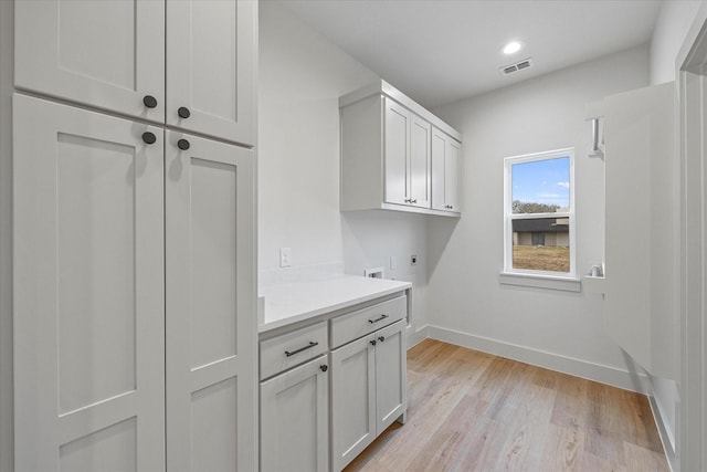 laundry area with cabinets, hookup for a washing machine, light hardwood / wood-style floors, and electric dryer hookup