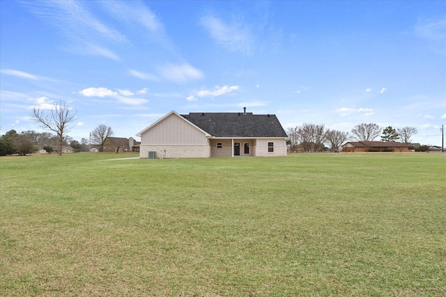 back of property with a yard and central AC