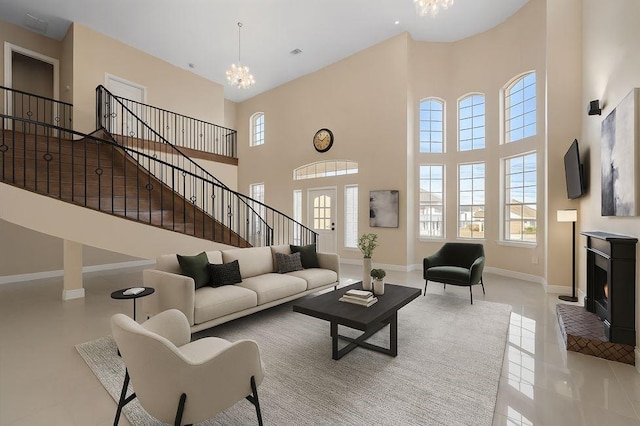 living area with baseboards, a high ceiling, an inviting chandelier, stairway, and tile patterned flooring