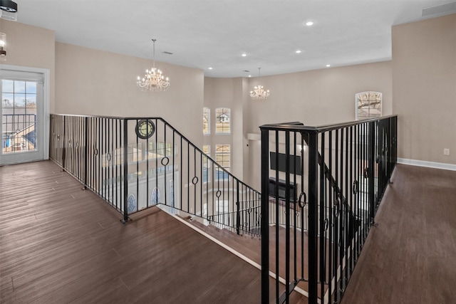 stairway with a chandelier, plenty of natural light, recessed lighting, and wood finished floors