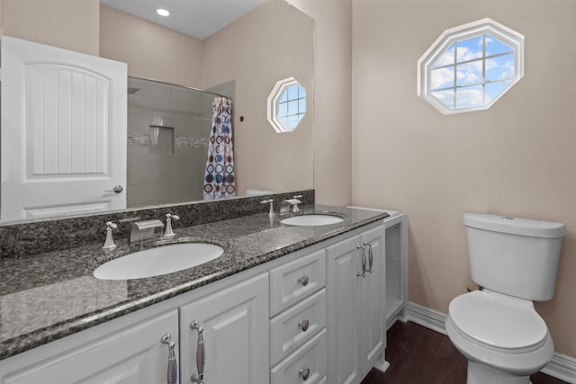 bathroom featuring a sink, toilet, double vanity, and baseboards