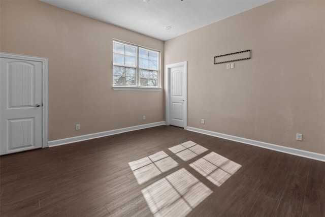 unfurnished room featuring dark wood-style flooring and baseboards