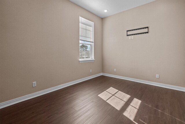 empty room with dark wood-style flooring and baseboards