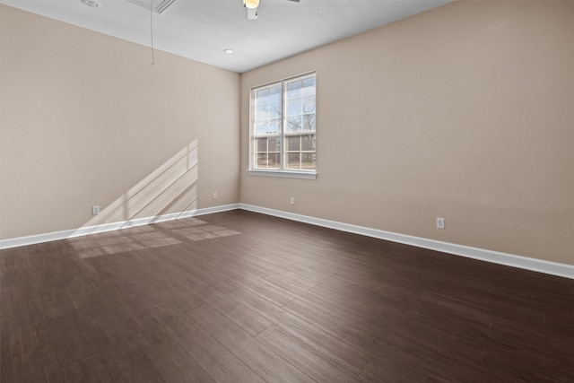 spare room with dark wood-style flooring, baseboards, a ceiling fan, and attic access